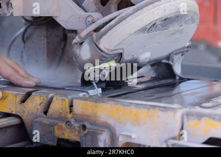 An employee cuts ceramic tile on wet saw with diamond blade Stock Photo