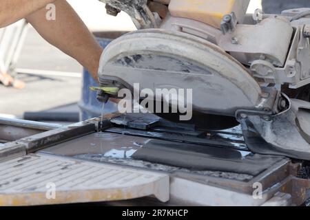 Cutting ceramic tile with circular diamond blade on wet saw machine Stock Photo