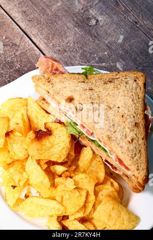 Bacon lettuce and tomato BLT sandwich with potato chip crisps isolated on a white plate Stock Photo