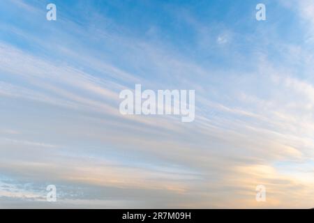 sunset sky with pink clouds, diagonally stripe, grey above. Whispy pink clouds and blue sky diving frame diagonally. Cirrus and cirrocumulus clouds fo Stock Photo