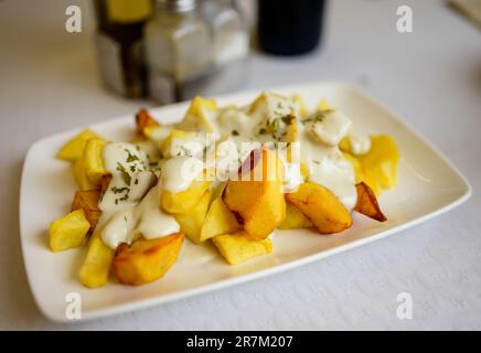 Asturian style roasted potatoes chips with melted blue cheese cabrales from Las Arenas village, Asturias, Spain Stock Photo