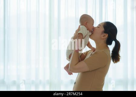 Asian mother playing with her newborn baby in bedroom at home. to promote family relations and good development of the baby Stock Photo