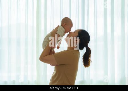 Asian mother playing with her newborn baby in bedroom at home. to promote family relations and good development of the baby Stock Photo