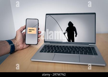 Silhouette of a hacker with a fishing rod on a laptop screen stealing personal data from a smartphone Stock Photo