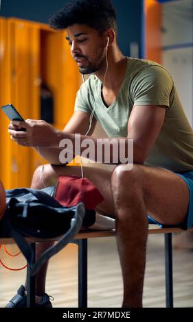Man, earphones and phone in gym for fitness, check wellness app or ...
