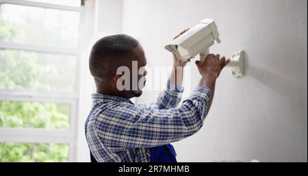 Close-up Of Technician Adjusting CCTV Camera On Wall Stock Photo