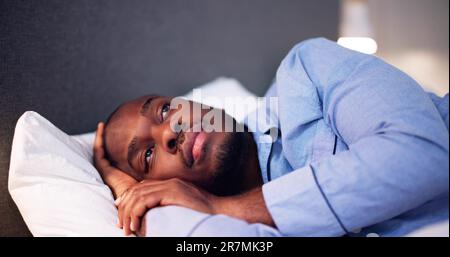Young African Man Suffering From Fever Lying On Bed Stock Photo