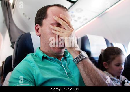 Young Man Having Anxiety Attack In Airplane Stock Photo