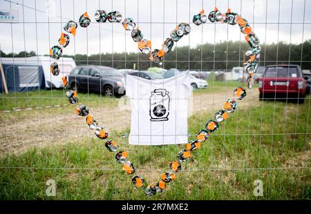 16 June 2023, Lower Saxony, Scheeßel: Empty beer cans in the shape of a heart hang from a fence at a Hurricane Festival campsite. The open-air festival with more than 80,000 visitors takes place from June 16 to 18. Photo: Hauke-Christian Dittrich/dpa Stock Photo