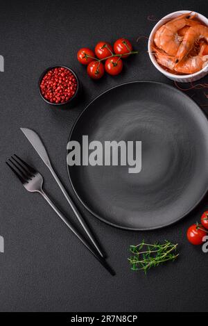 Ingredients for cooking cherry tomatoes, shrimp, salt and spices with a place for an inscription on a dark concrete background Stock Photo