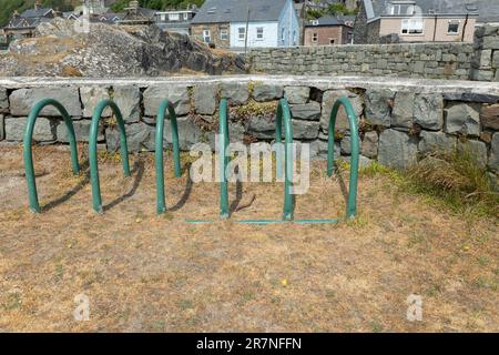 green Metal cycle rack or stands on hardstanding beside grass lawn Stock Photo