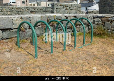 green Metal cycle rack or stands on hardstanding beside grass lawn Stock Photo