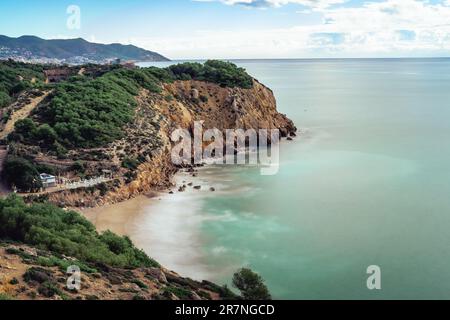 Nice cliff in the mediterranean sea near Sitges and Vilanova i la Geltru, spain. Long exposure photography on a sunny day overlooking the dead man's b Stock Photo