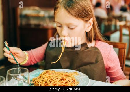 Adorable little girl eating spaghetti with bolognese sauce in the restaurant Stock Photo