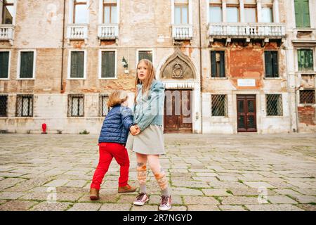 Outdoor portrait of cute little boy and girl, stylish kids playing together. Fashion for small children Stock Photo