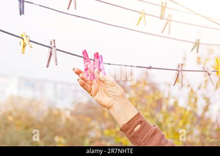 Laundry woman hangs clean wet cloth on clothes dryer after washing at home. Household chores and housekeeping Stock Photo