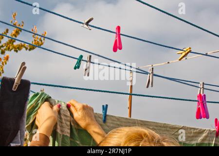 Laundry woman hangs clean wet cloth on clothes dryer after washing at home. Household chores and housekeeping Stock Photo