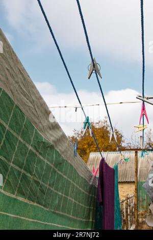 A clothespin hangs on the washing line. A rope with clean linen and clothes outdoors on the day of the laundry. Against the background of green nature Stock Photo