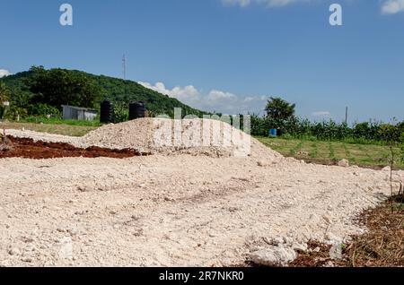 During the construction of a roadway marl is dumped on the path in heaps and some spread along the roadway. Stock Photo