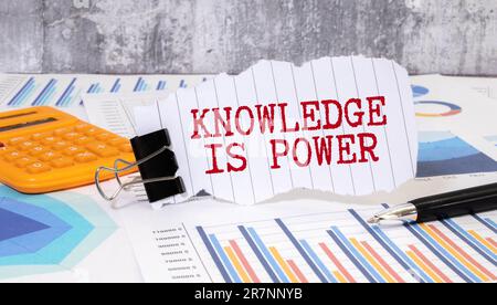 Concept:Knowledge is power written on torn paper with black background and pen. Stock Photo