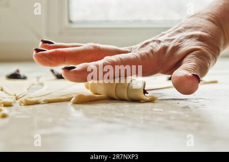 Sliced raw mixed dough with berries lies on the baking tray. cooking baking dish. women's hands roll the dough on a bagel Stock Photo