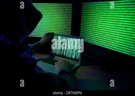 Hacker working with computers at wooden table indoors. Cyber attack Stock Photo