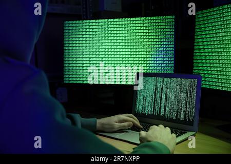Hacker working with computers at wooden table indoors, closeup. Cyber attack Stock Photo