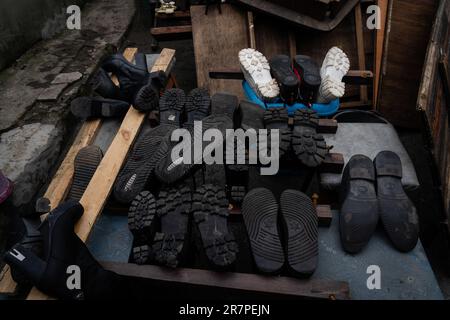 Shoes with rubber soles are seen hanging outside the house in