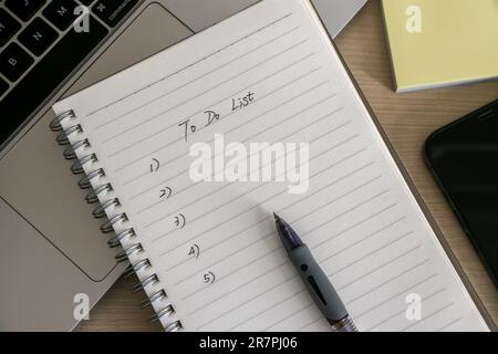 Organization and To Do List concept, workplace with notepad, ballpoint pen, some sticky notes, a laptop and smartphone, on wooden desk. Checklist for Stock Photo