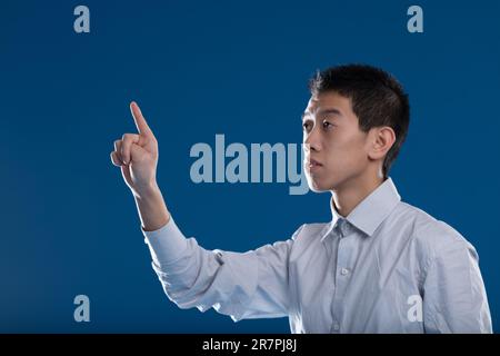 Asian man's fingertip in sharp focus, typing in a blurry background. Perfect canvas for your graphics and COPYSPACE. Interacts with AI and neural inte Stock Photo