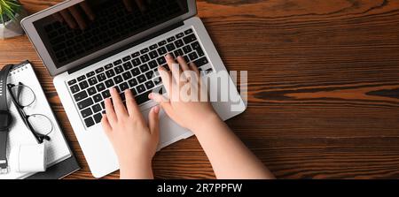Female programmer using laptop at wooden table, top view Stock Photo