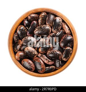 Scarlet Runner beans in a wooden bowl. Dried and raw runner beans, seeds of Phaseolus coccineus, also known as multiflora bean or butter bean. Stock Photo