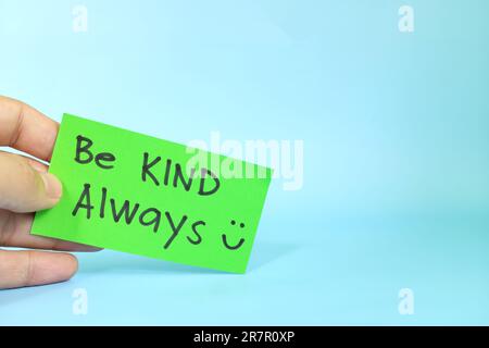 Be kind always and kindness reminder concept. Hand holding a bright green paper message note. Stock Photo