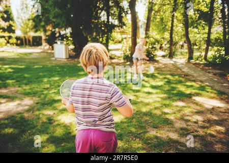 Group of 2 funny kids friends playing badminton in summer park. Children having fun together on a nice sunny day Stock Photo