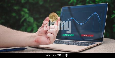 Laptop with chart and bitcoin in hands. Cryptocurrency gold coin, stock exchange graph Stock Photo