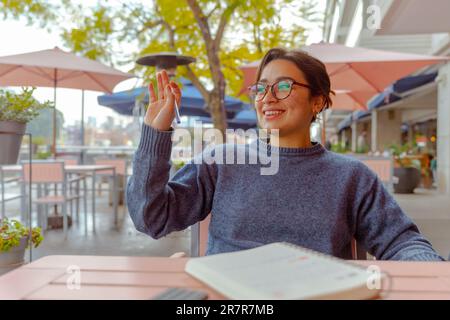 A cheerful young woman is sitting in a cozy cafe during the winter season, her bright smile illuminating the room Stock Photo