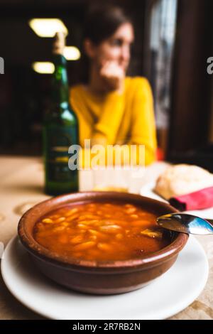 Asturian delight, Fabada Asturiana, a traditional Spanish dish featuring white beans, sausages, and pork, accompanied by a bottle of fine wine Stock Photo