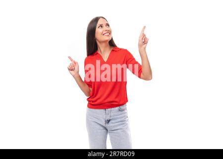 young inspired caucasian brunette woman in a red short sleeve shirt points with her hands to the sides Stock Photo