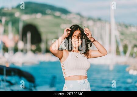 outdoor fashion portrait of beautiful youn woman posing by the lake 2r7remc
