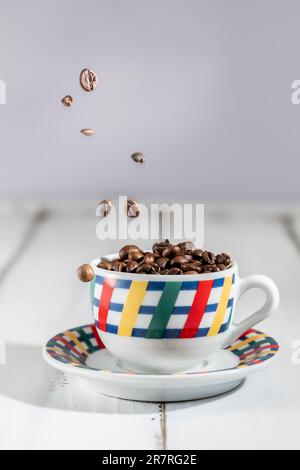 Coffee beans fly into a colorful espresso cup Stock Photo