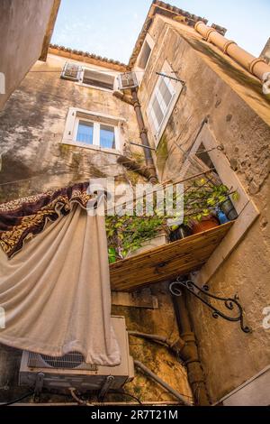 Historic residential buildings in the old centre of Split in Croatia. A bamboo platform forms a shelf between two windows for plants Stock Photo