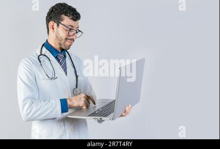 Handsome doctor using laptop isolated. Young doctor in glasses using notebook on isolated background, Smiling doctor standing using laptop isolated Stock Photo