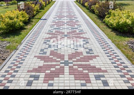 A beautiful path paved with paving slabs in the form of an embroidered Ukrainian ornament. Stock Photo