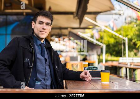 Handsome man looking at camera while smiling after drinking a coffee at a bar Stock Photo