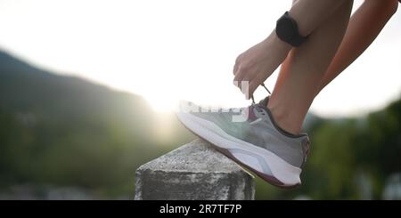 Running shoes. close up female athlete tying laces for jogging on road. Runner ties getting ready for training. Sport lifestyle. copy space Stock Photo