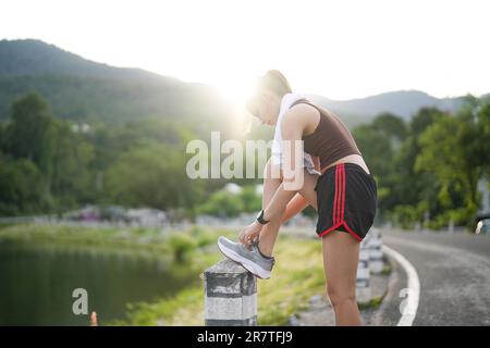 Running shoes. close up female athlete tying laces for jogging on road. Runner ties getting ready for training. Sport lifestyle. copy space Stock Photo