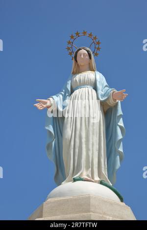 White statue of Our Lady with crown and halo, St-Sauveur, Saint, Madonna figure, sculpture, blue, gesture, arms, cut-out, sky, Fos-sur-Mer, Provence Stock Photo