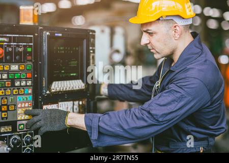 Caucasian Engineer Male Skill Worker Working Operate CNC Lathe Machine In Metal Factory. Stock Photo