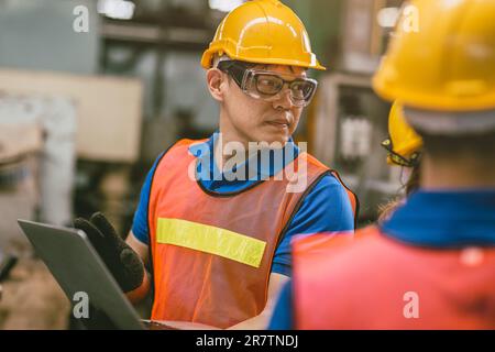 Professional Engineer Worker Male Asian working with teammate as Machine Programmer in Metal Factory Candid shot. Stock Photo