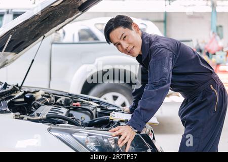 Asian male mechanic garage staff worker car engine service in auto shop happy smiling portrait Stock Photo